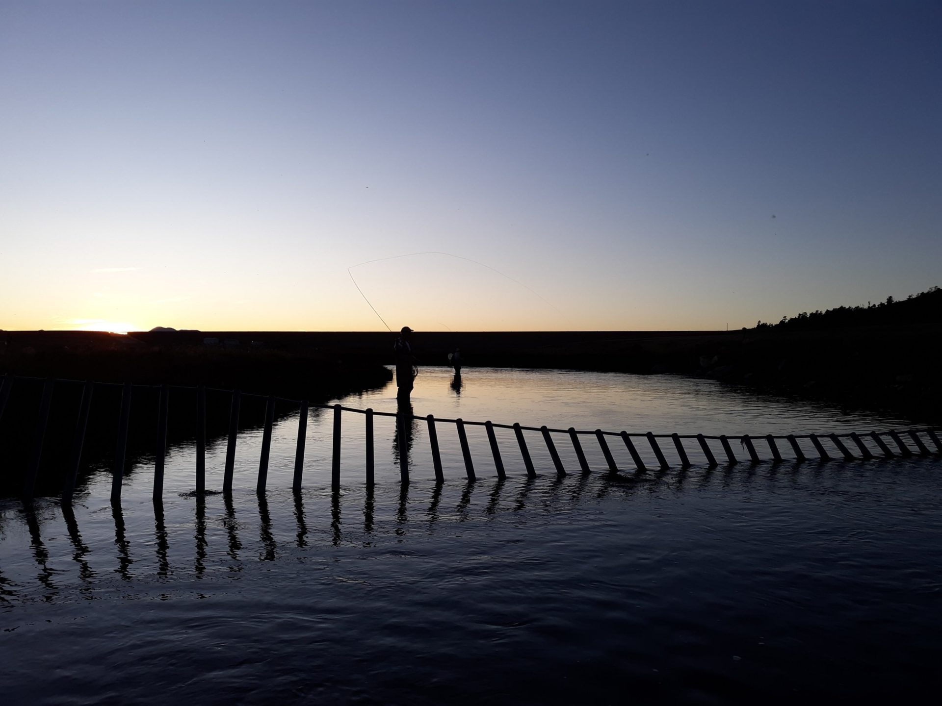 Two anglers casting on a Colorado river at dusk